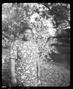 1937 Photo of Vera Hall standing outside.